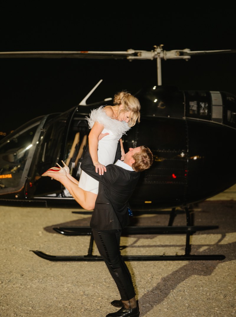 Couple celebrating beside a helicopter at night